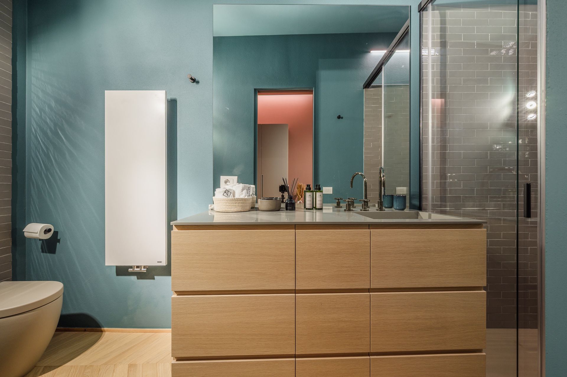 Turquoise bathroom vanity, mirror reflecting the pink bathroom in the background