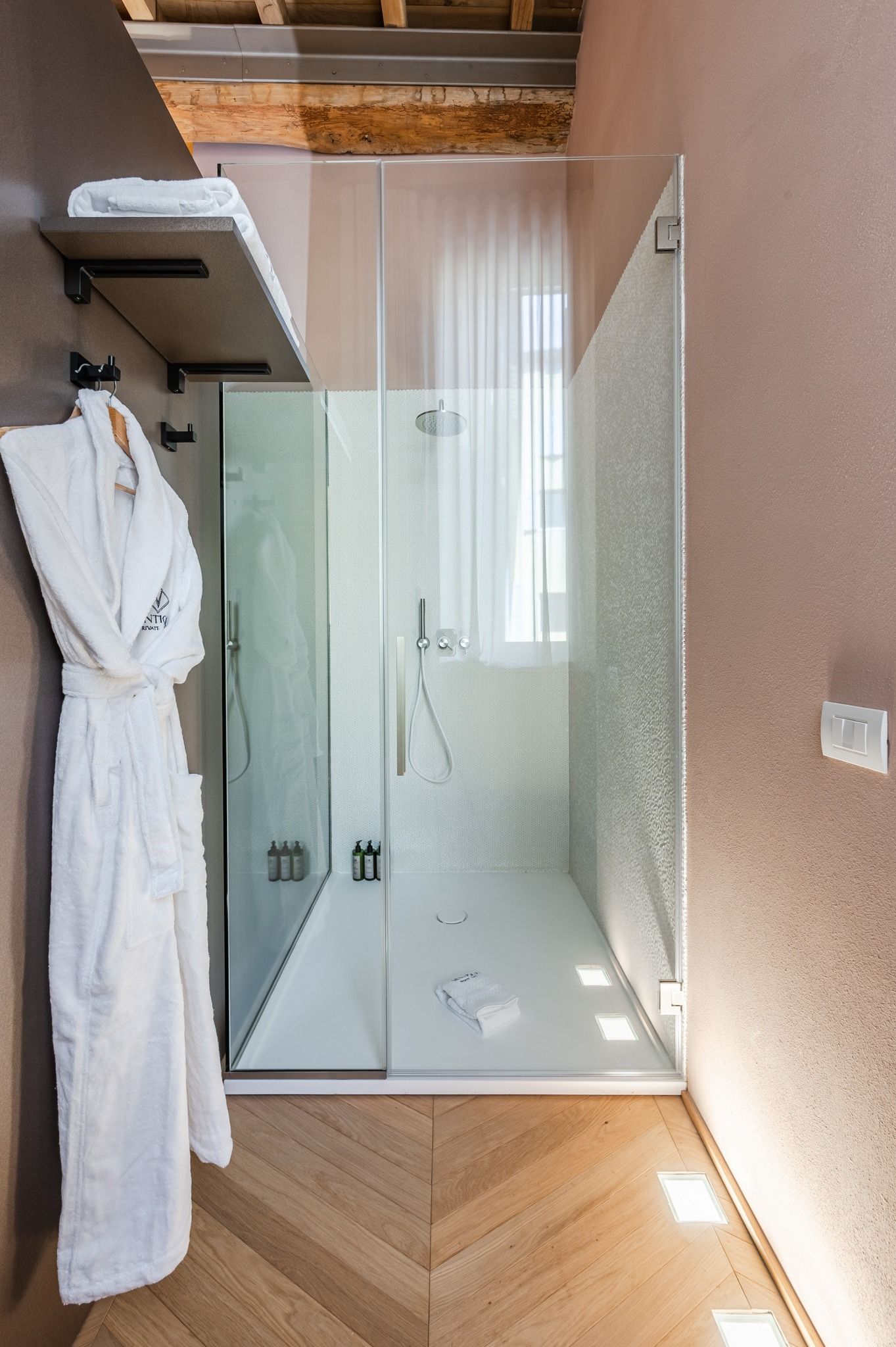 Walk-in shower with a bathrobe hanging alongside