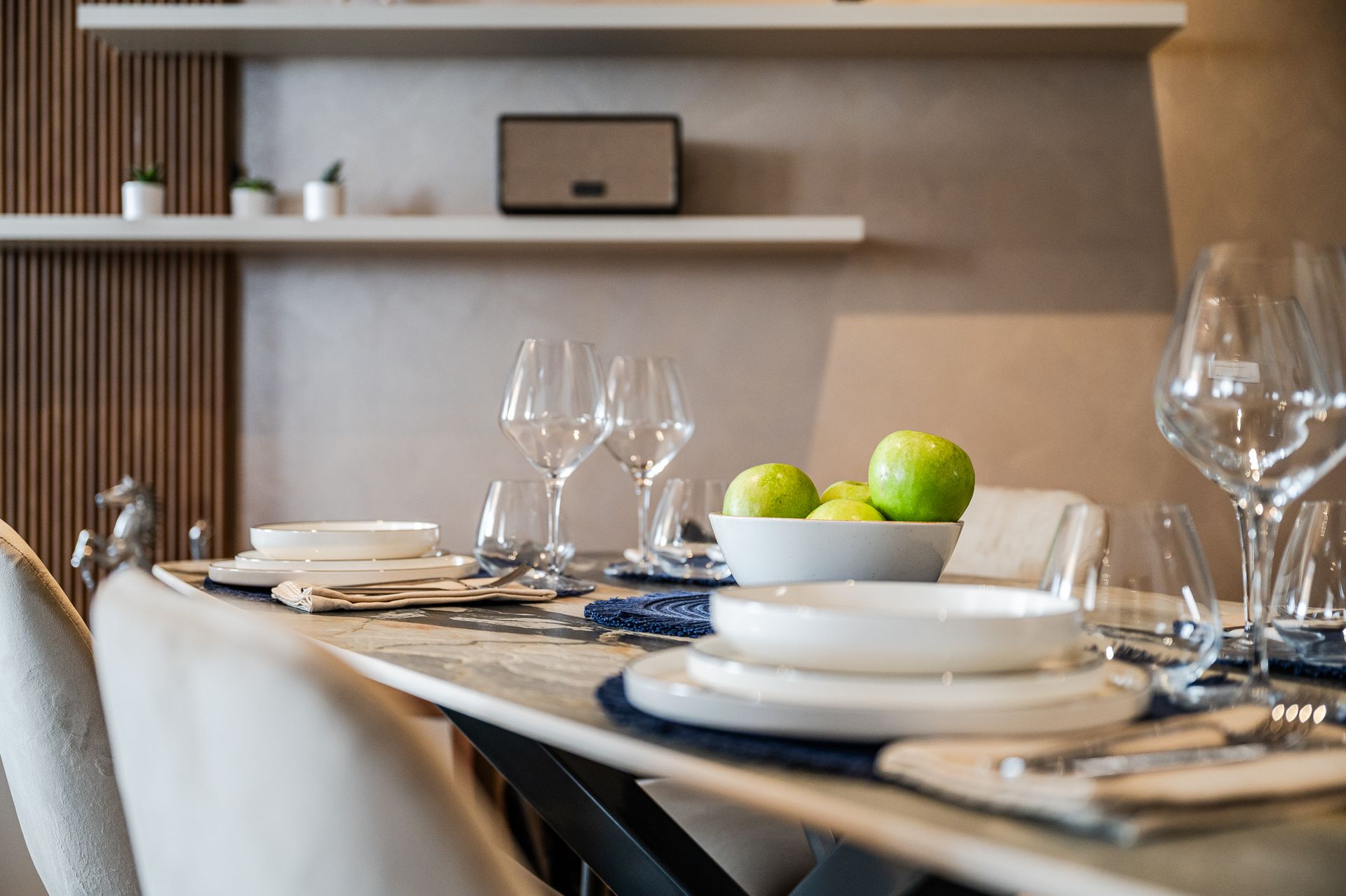 Detail of the set dining table with wine glasses and a bowl of green apples