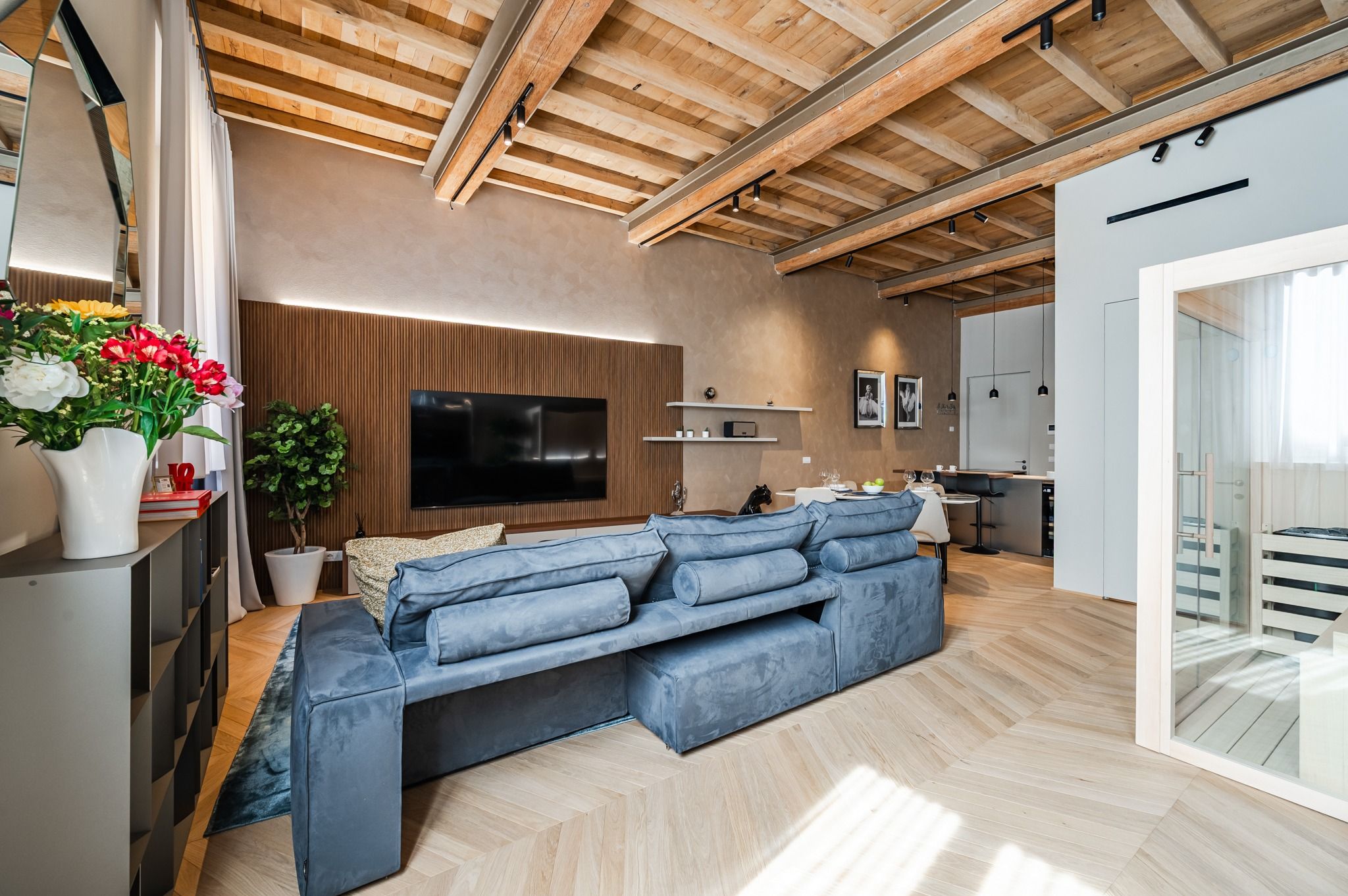 Living room with blue sofa, exposed beams and the sauna at the far end