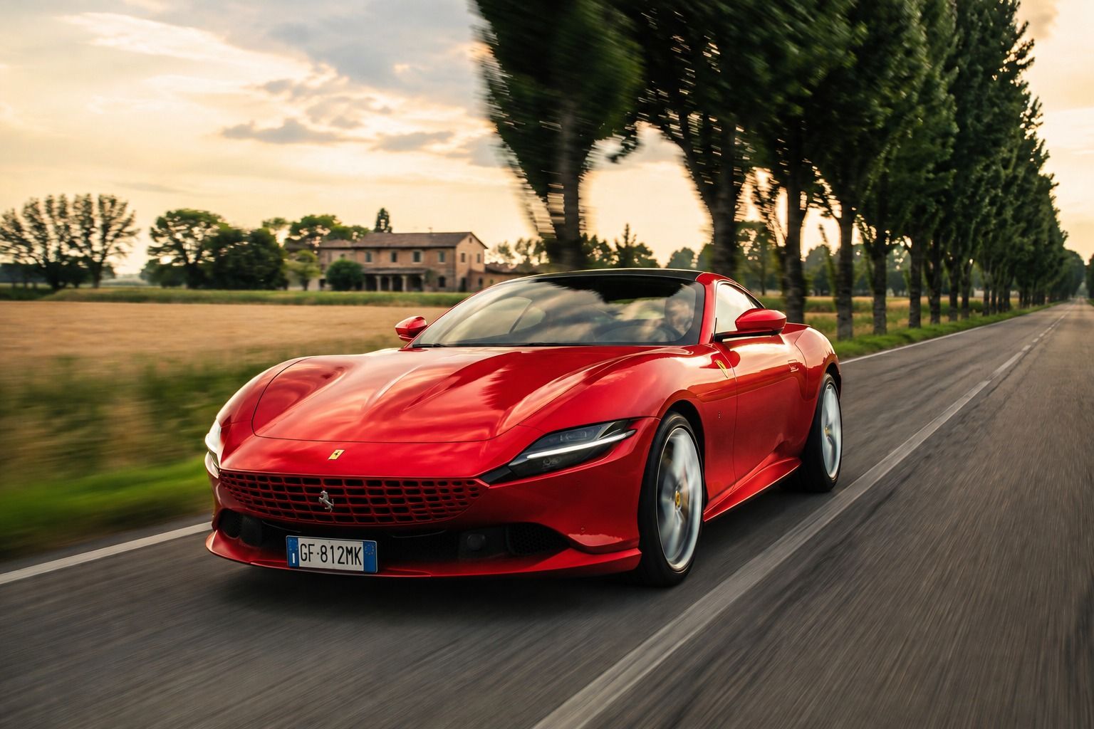 A red Ferrari Roma on the move along a country road