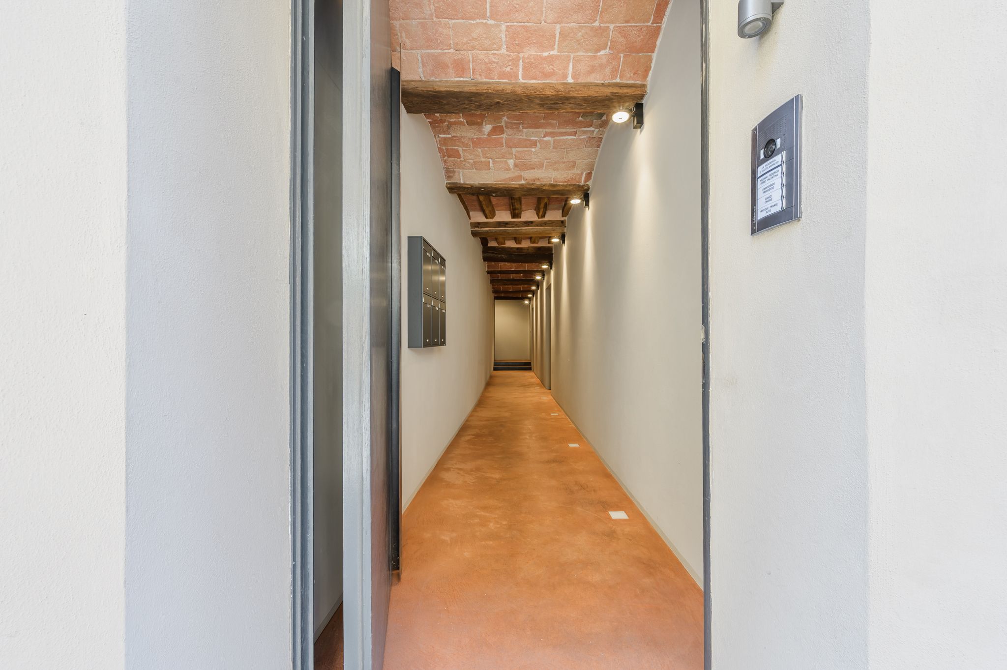 Androne d'ingresso del palazzo con volte in mattoni a vista, cassette postali e citofono